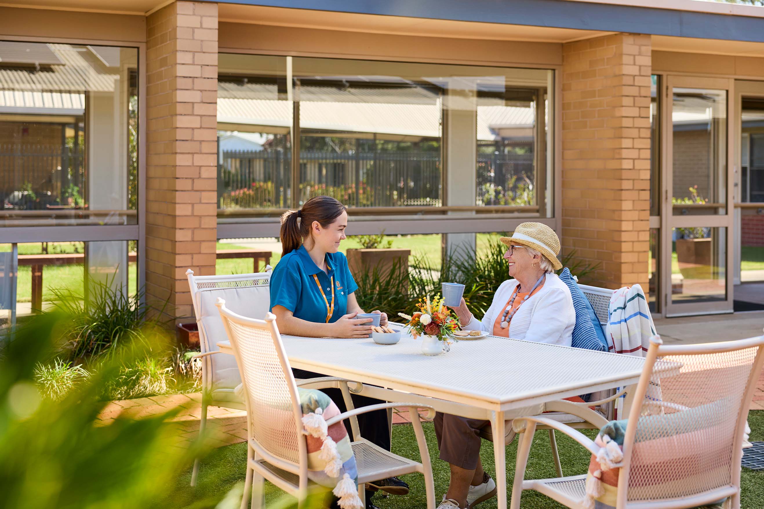Resident and Benetas team member enjoying a drink together in the internal courtyard at Benetas Eaglehawk