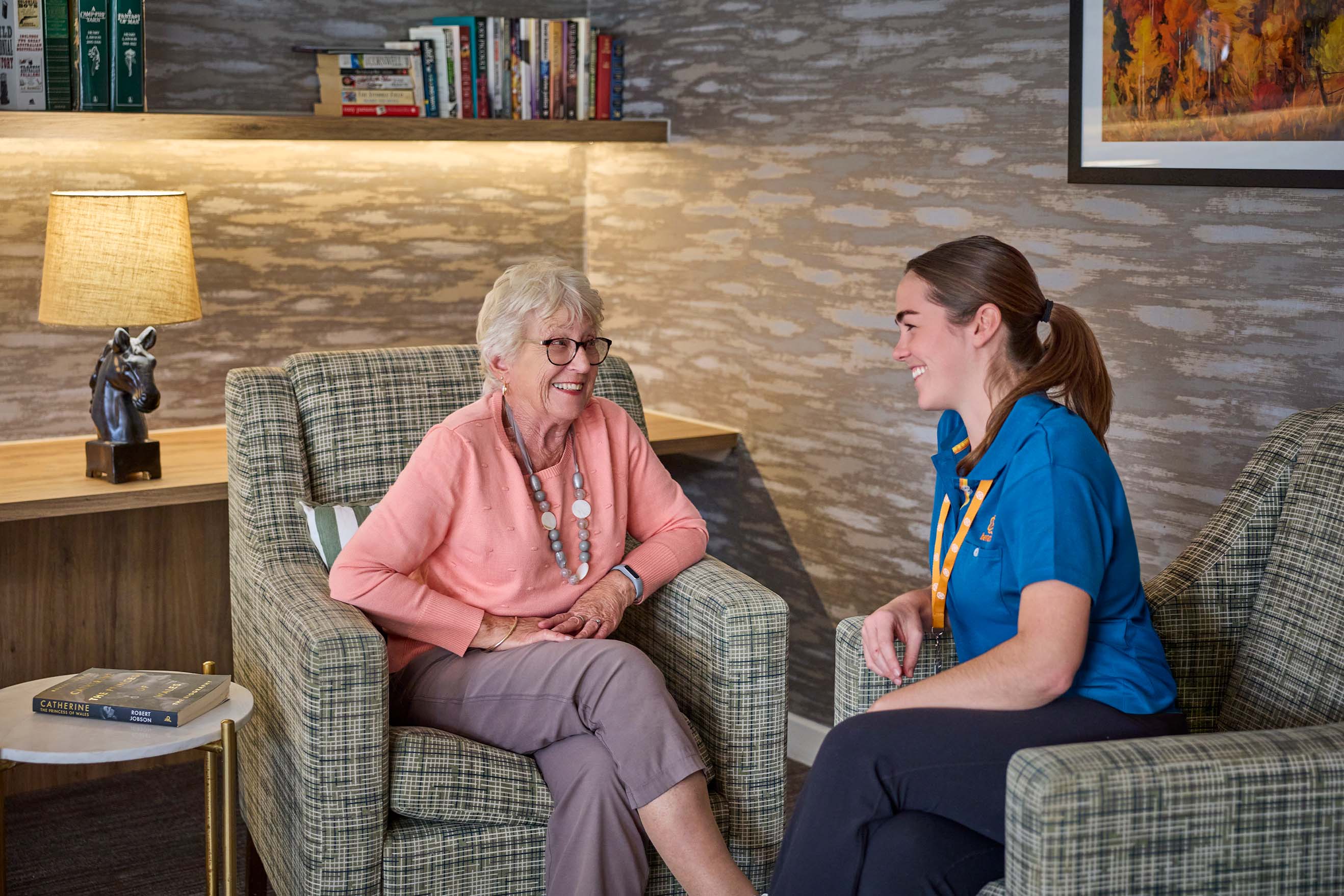 Resident and Benetas team member talking together in the library at Benetas Eaglehawk