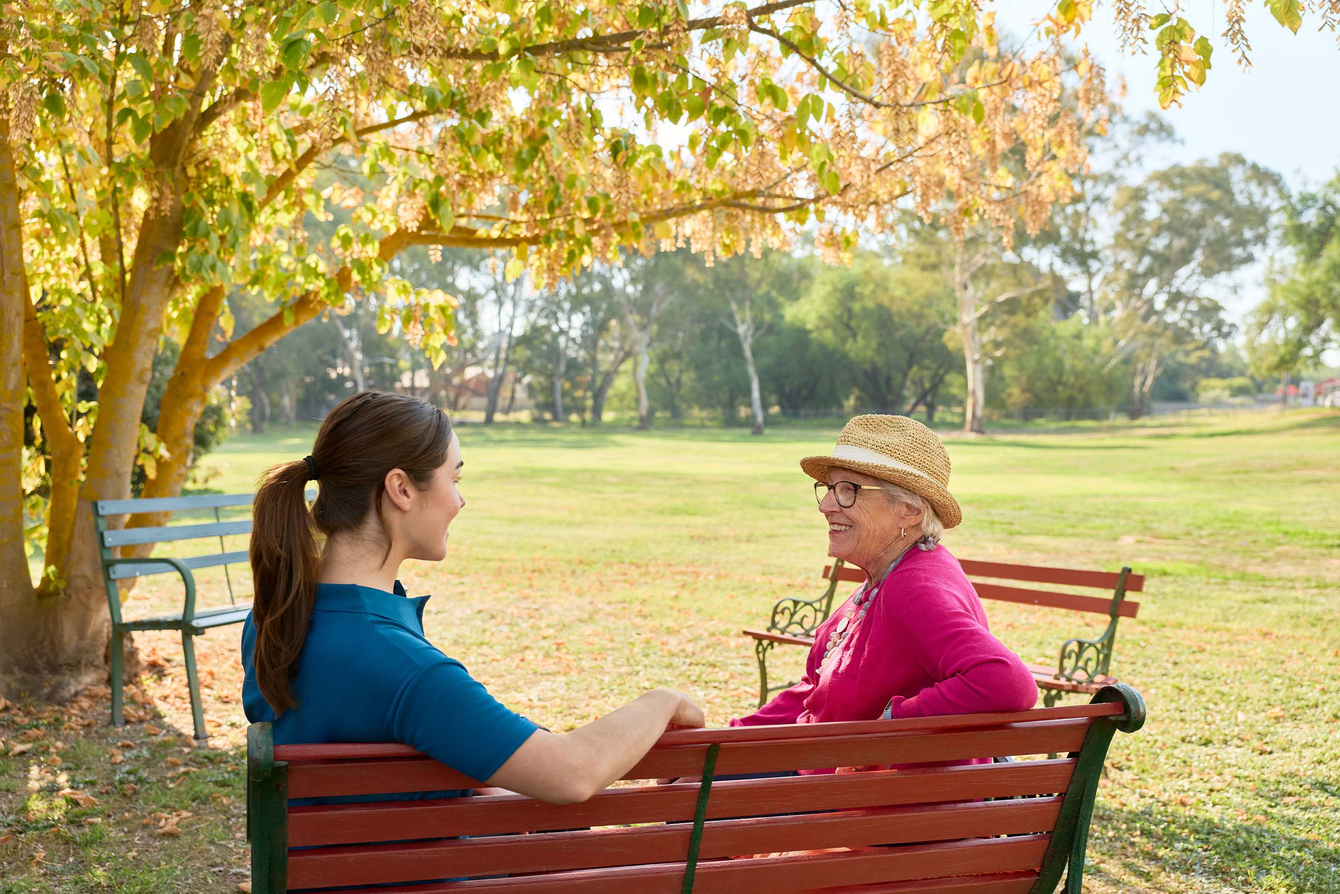 Resident and Benetas team member sitting together on a bench in the outdoor garden space at Benetas Kangaroo Flat