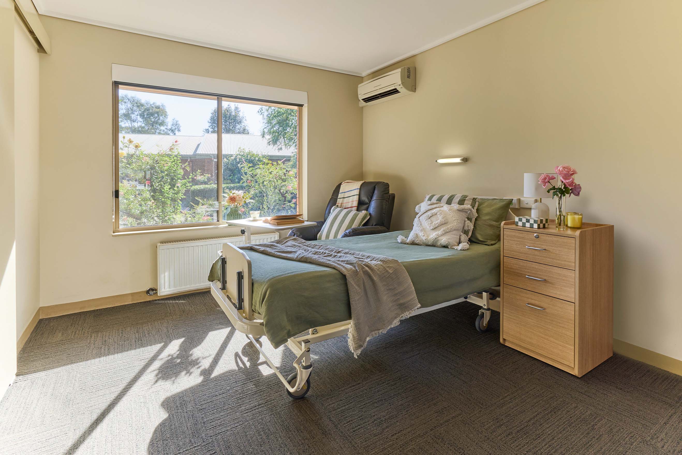 Bright private resident room with bed, armchair, bedside table and garden view at Benetas Kangaroo Flat