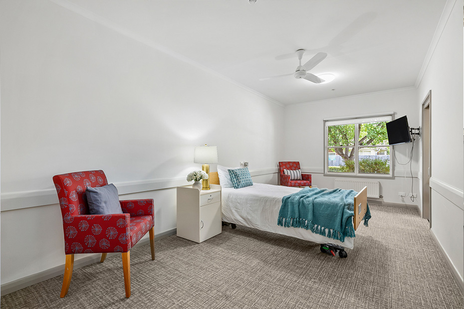 A cozy bedroom with a comfortable bed, a chair, and a desk for work or study purposes.
