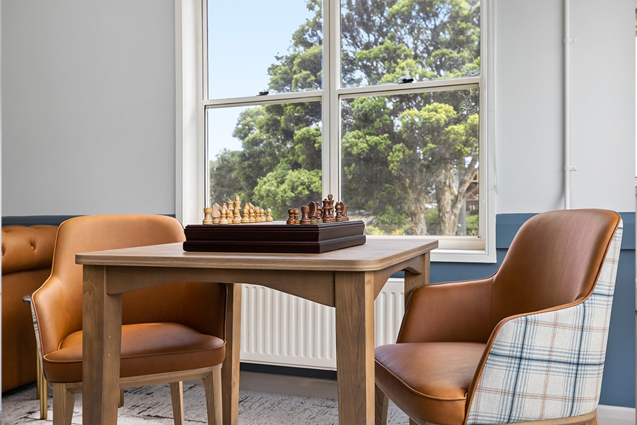 A chess board set on a table with two chairs nearby, inviting a game of strategy and intellect.