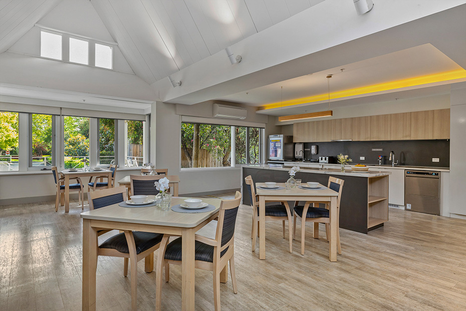A well-lit kitchen with a wooden dining table and chairs, creating a cozy and inviting atmosphere.