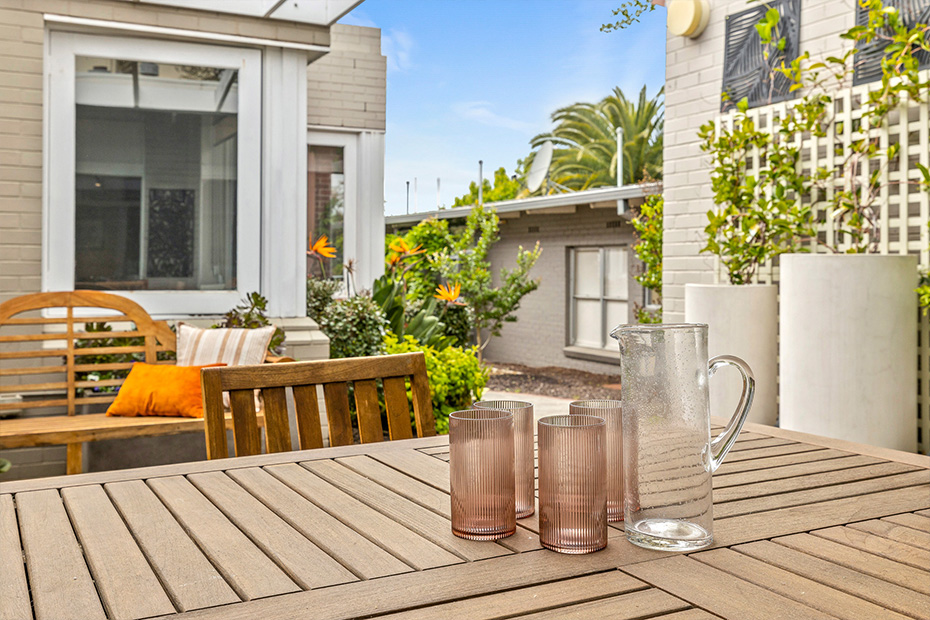 A wooden table with a glass pitcher and two vases on it, creating an elegant and rustic display.