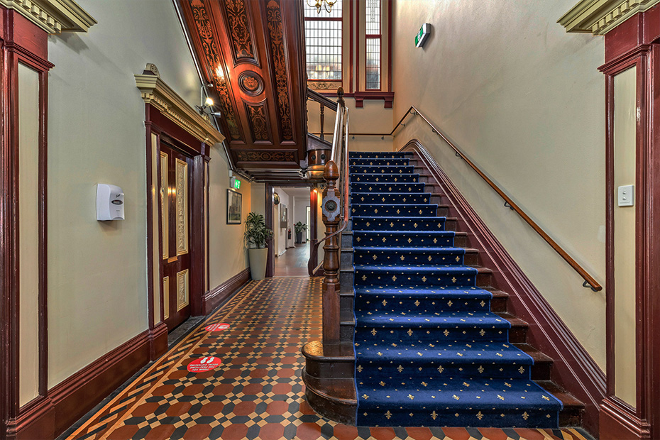 A staircase with blue carpet and intricate woodwork, adding elegance to the overall design.