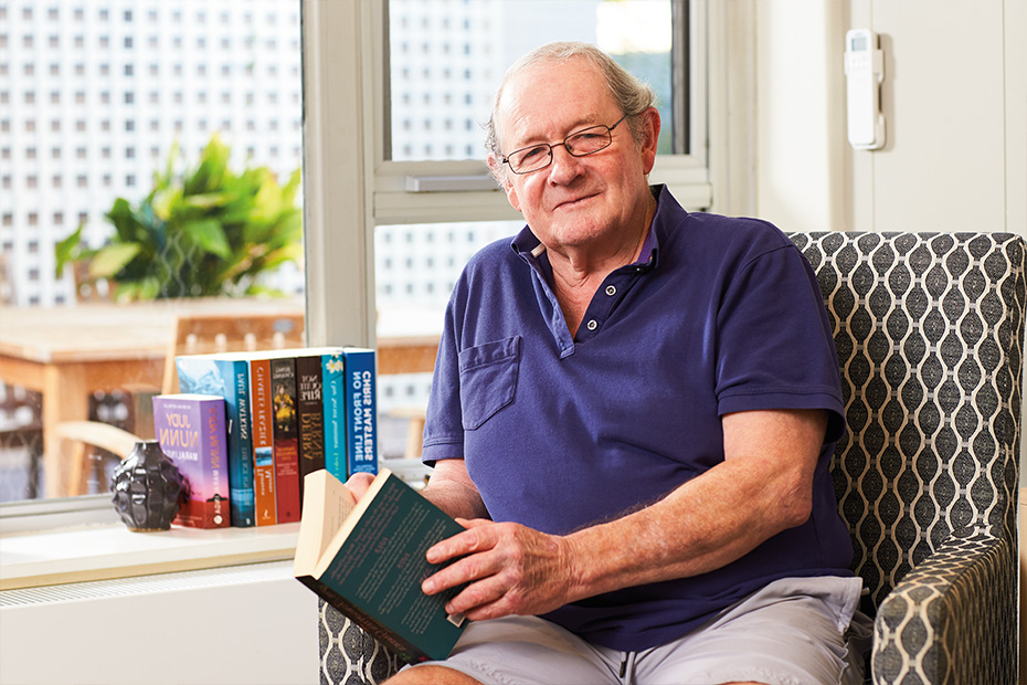 A senior man captivated by a book, seated in a chair.