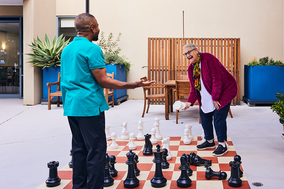 A couple engaged in a strategic battle of chess on a patio, showcasing their intellectual prowess.