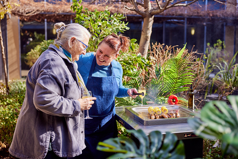 Two women grilling outdoors, preparing delicious food on a barbecue.