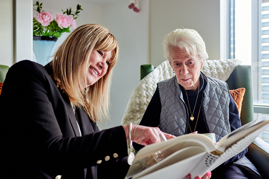 A woman reading a book to her mother, sharing a moment of connection and knowledge.