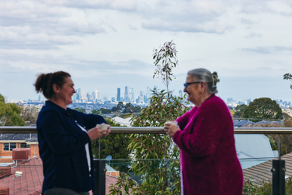 Two women enjoying the view from a balcony, overlooking the surroundings.