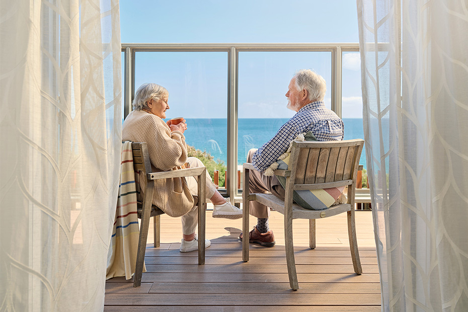 Two residents sitting on the terrace at Benetas Corowa Court, sharing a quiet moment with stunning views of the bay on a sunny day.