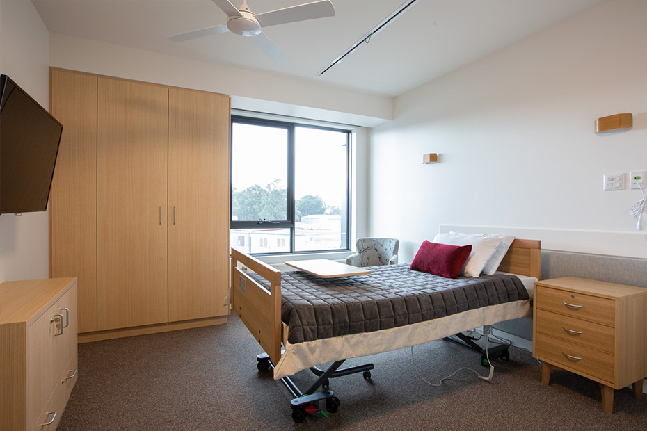 A clean and organised room with a bed, TV, and desk.