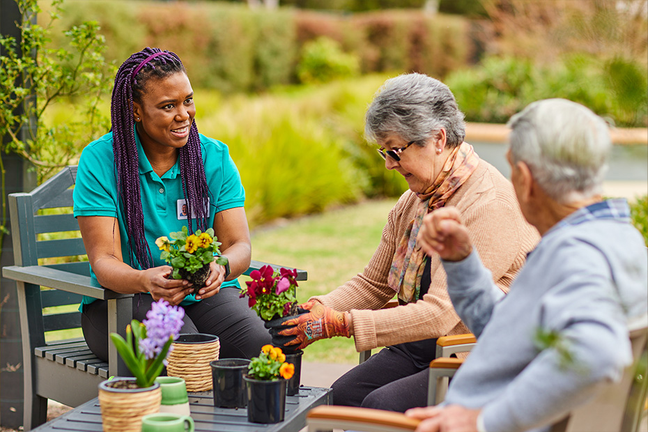 A young woman assisting an older lady in gardening, showing care and support in outdoor activities.