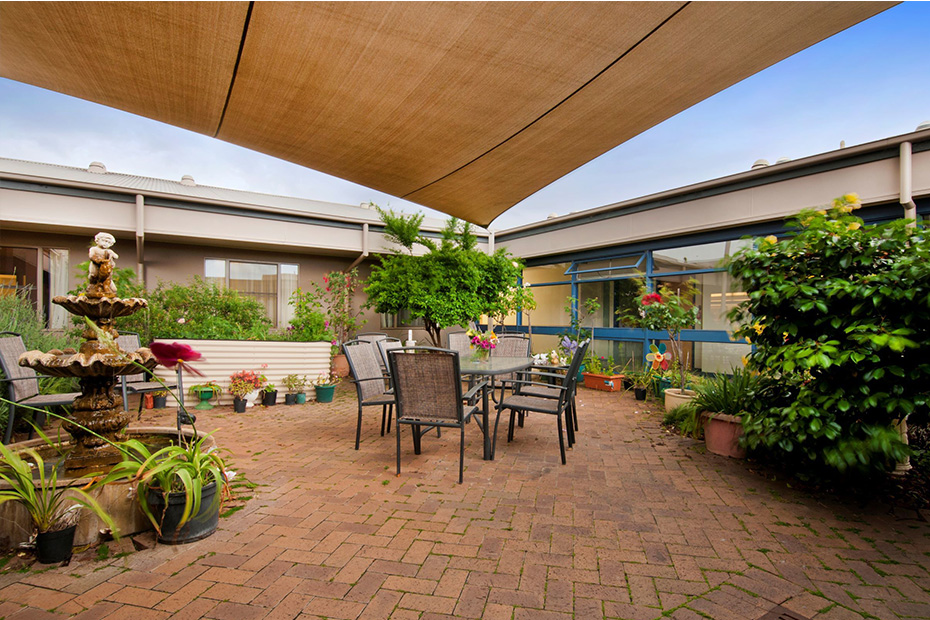 A serene patio with a table, chairs, and a charming fountain, perfect for relaxing and enjoying the outdoors.