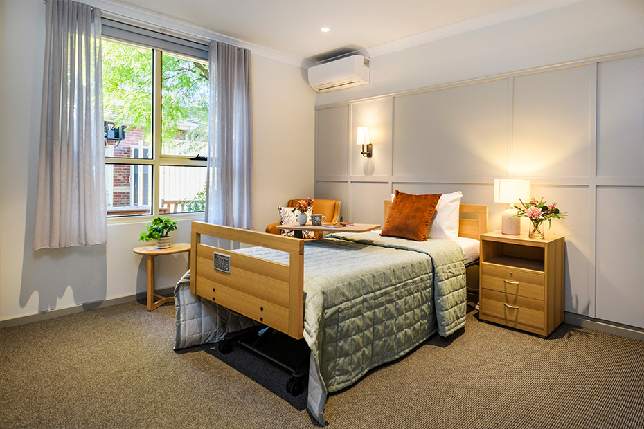 A cozy bedroom with a comfortable bed, a functional desk, and a window offering natural light.