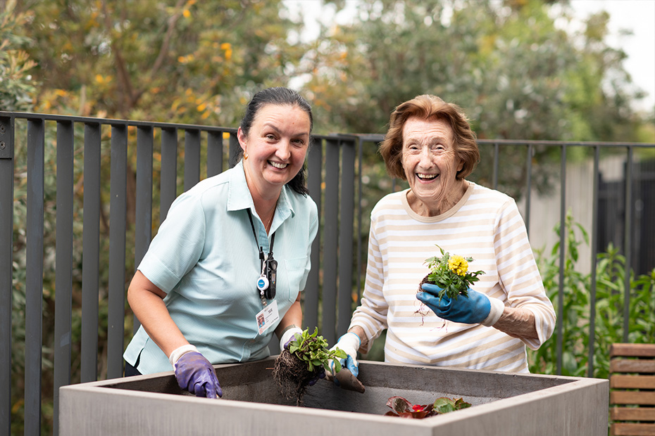 A woman and an older woman happily hold plants, radiating joy and contentment.