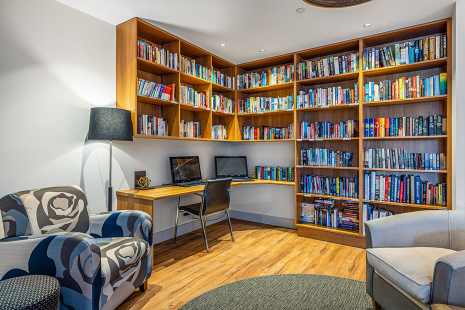 A well-furnished room with a chair, desk, and large bookcases.
