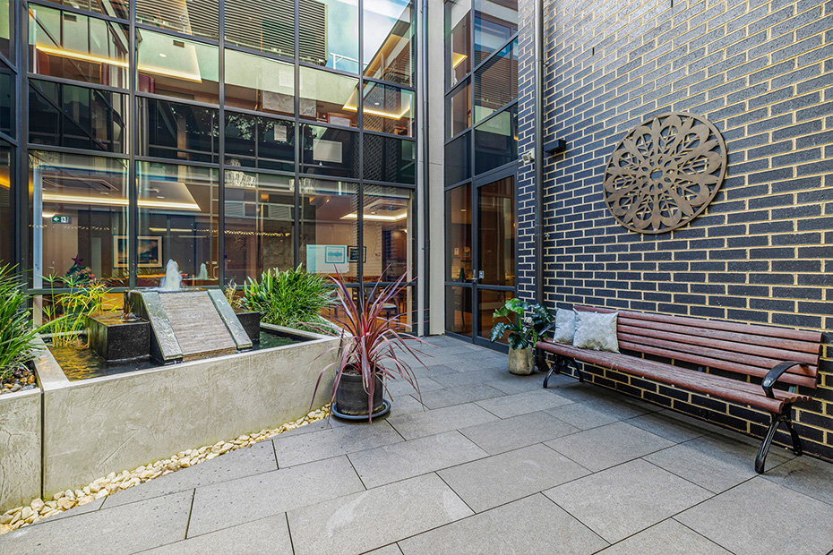 A bench in front of a building with a wall - a peaceful spot to rest and enjoy the surroundings.