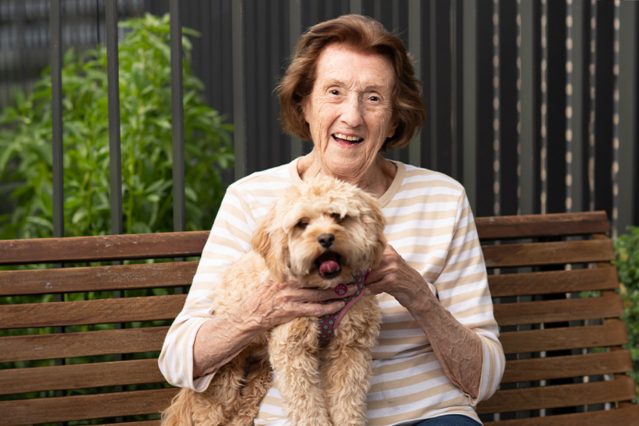 An resident woman enjoying the company of her loyal dog while sitting on a bench.
