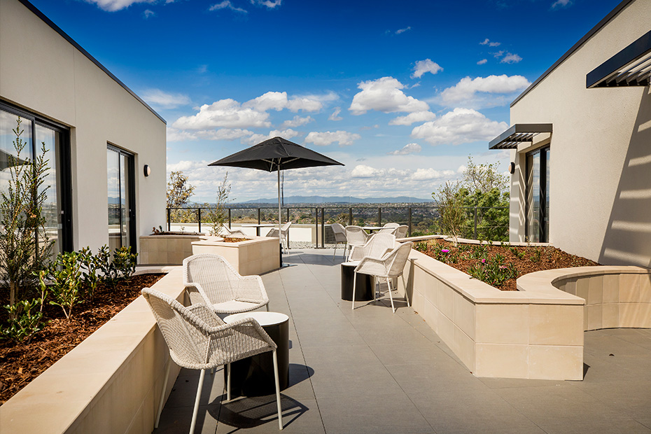 A patio with a table, chairs, and an umbrella providing shade.