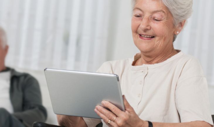 An older woman engages with a tablet, showcasing her connection to technology and independence.