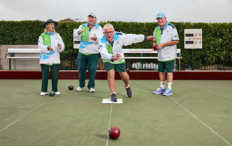 A group of people playing bowls on a green field.