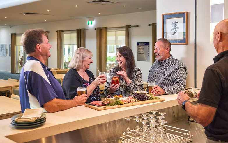 A diverse group of individuals happily together at happy hour, savoring delicious food and engaging in lively conversations.