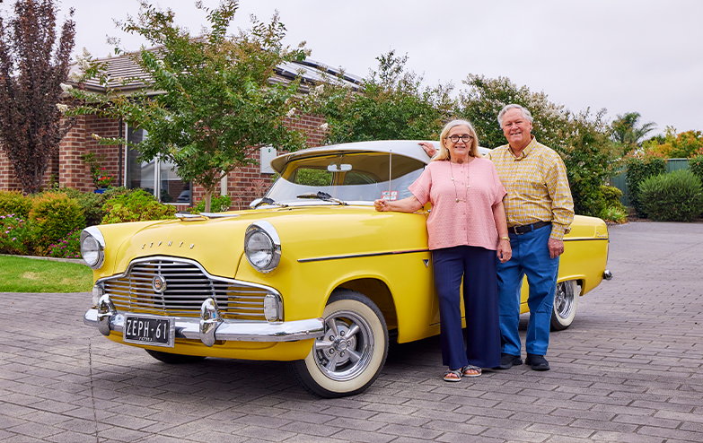 A couple posing beside a vibrant yellow car, exuding a sense of joy and adventure.