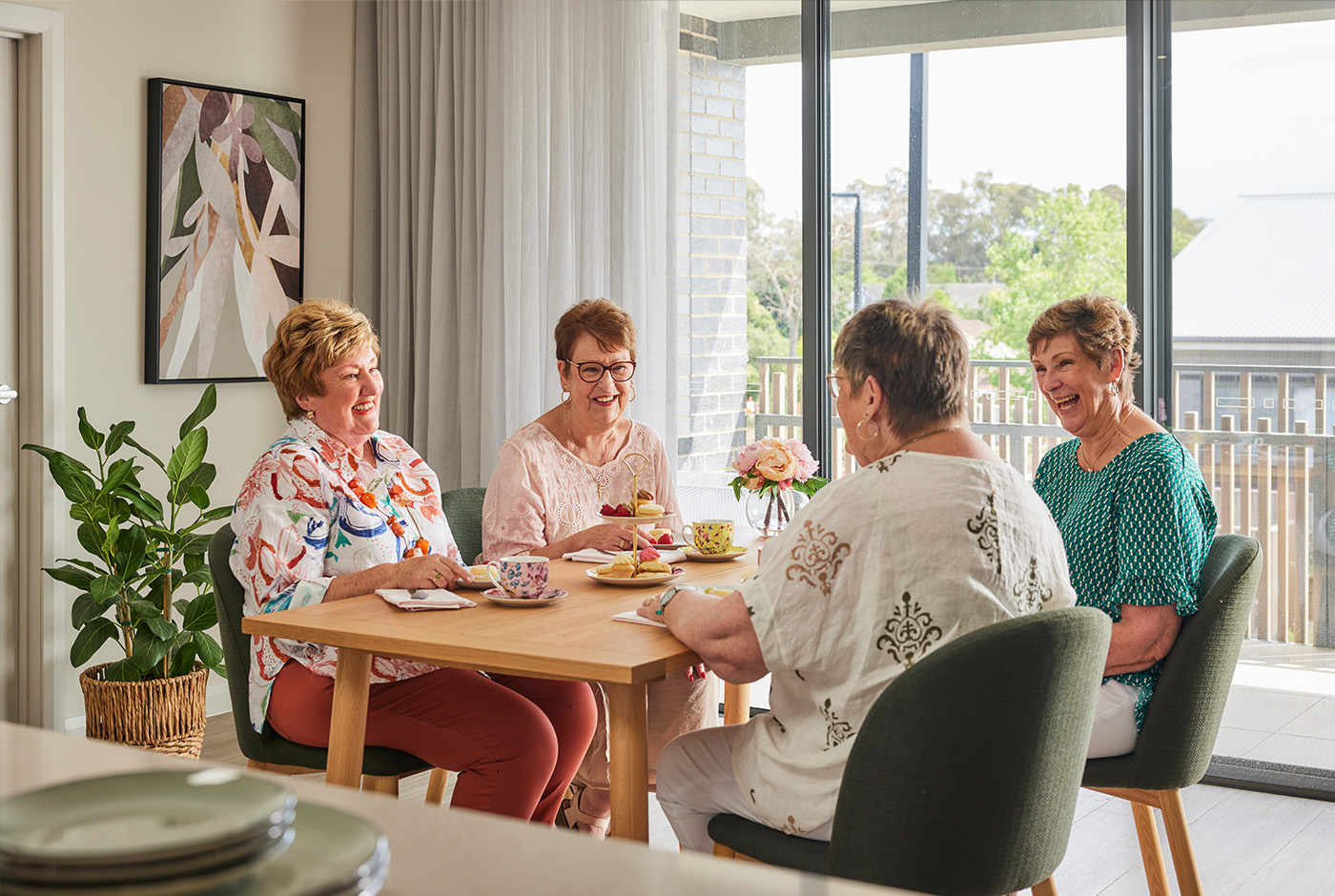  Four women sitting at a table in a room, engaged in conversation and enjoying each other's company.