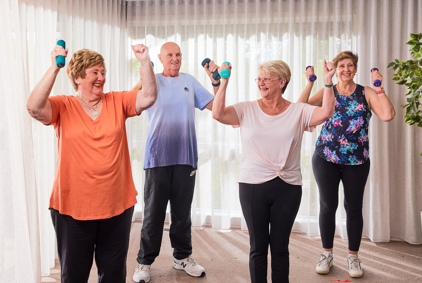 A diverse group of older individuals engaging in a workout routine, lifting dumbbells to maintain their physical fitness.