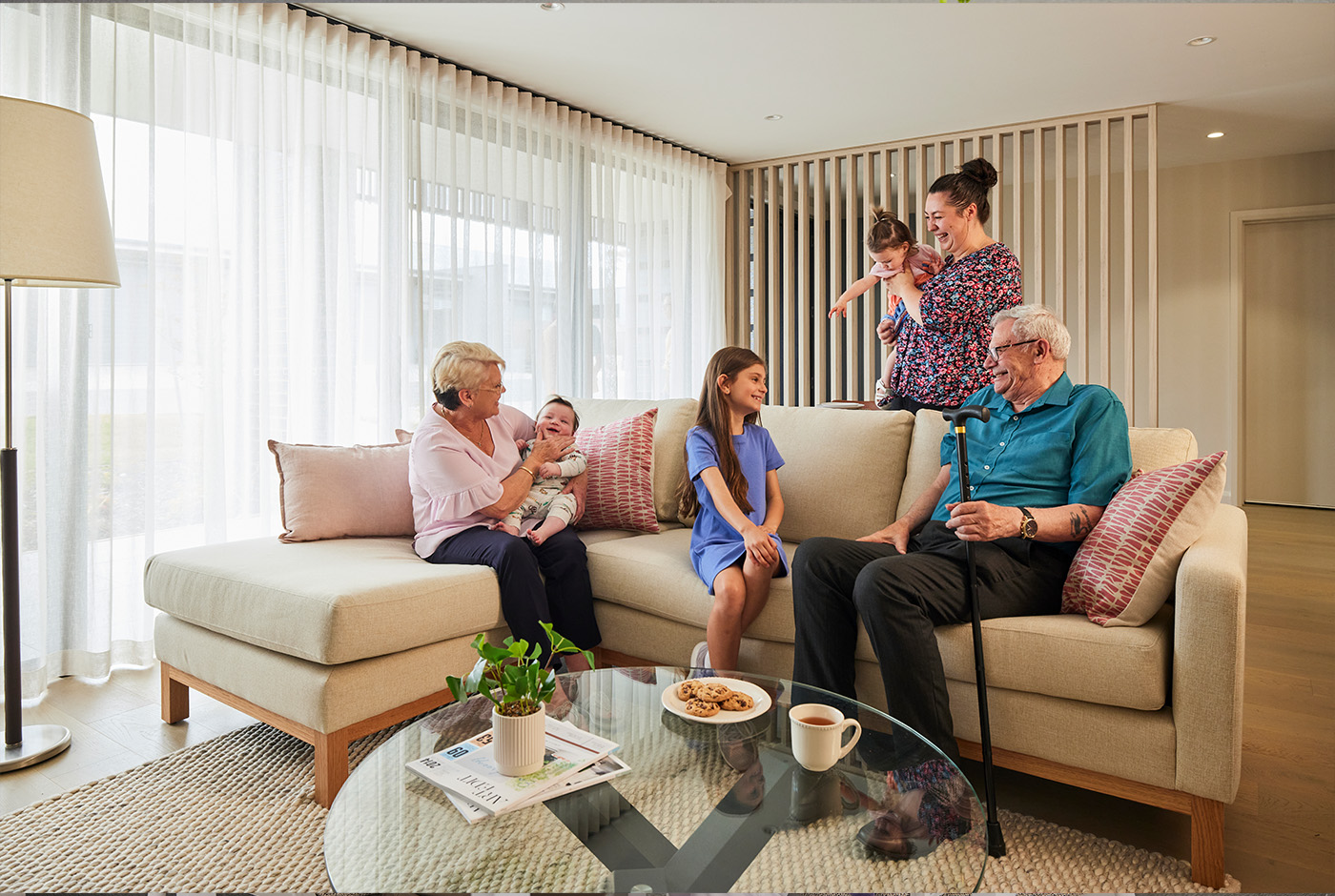 A family of four sitting on a cozy couch in a well-decorated living room, enjoying each other's company.