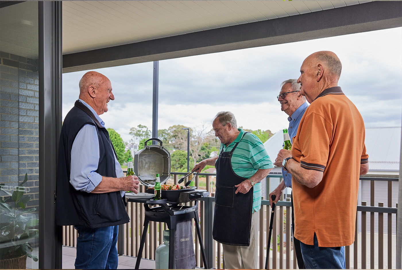 Three men grilling on a balcony.