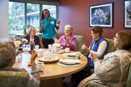 A joyful gathering of seniors at a table, capturing a special moment as a woman snaps a photo.